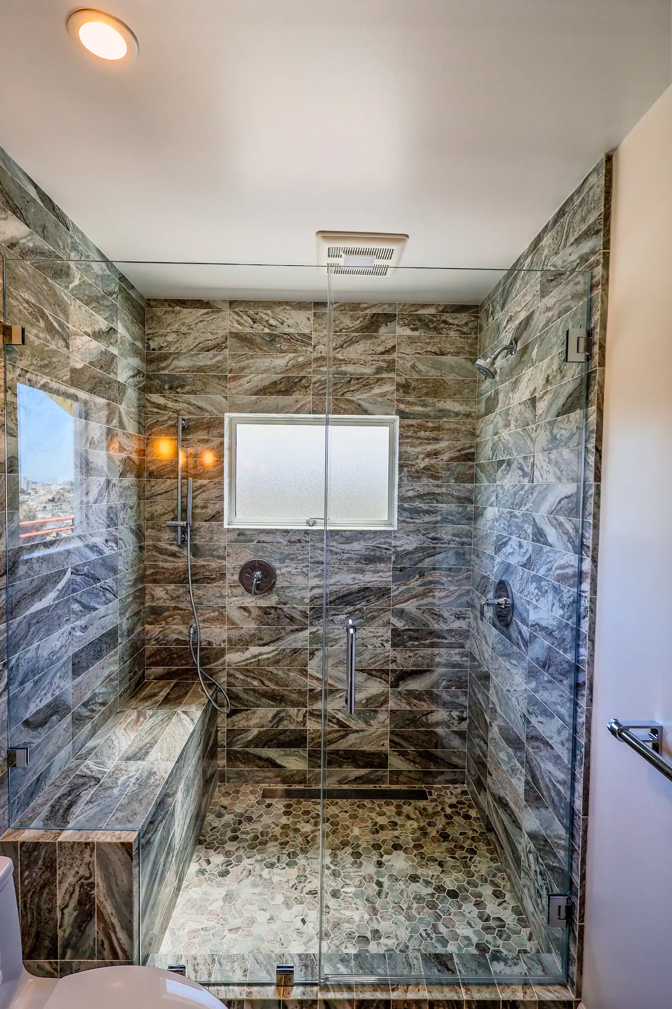 Stone walk-in shower with bench